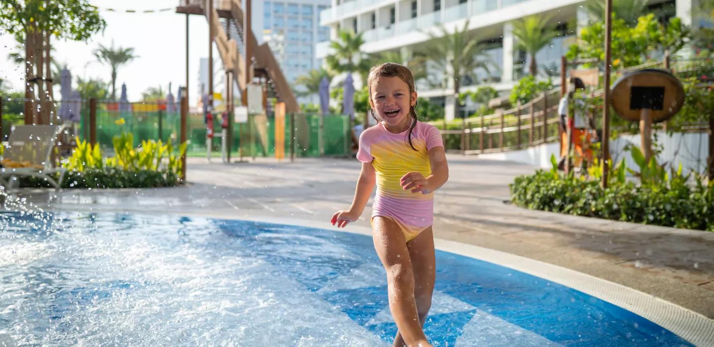 A girl playing in splash pad area at Centara Mirage Beach Resort Dubai CDD