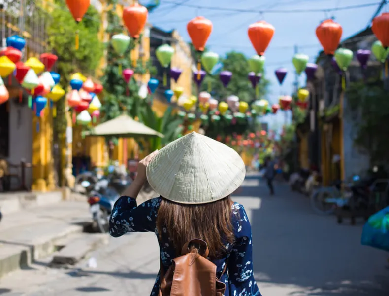 A woman wearing a traditional hat and exploring Vietnam