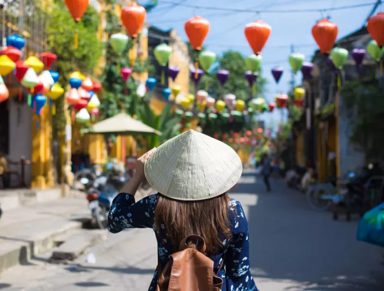 A woman wearing a traditional hat and exploring Vietnam